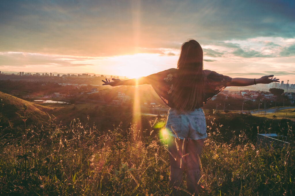 Lady standing with her arms open watching the sunrise