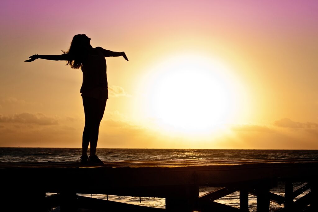 Woman with arm out to the sun.How to use Biohacking to improve your Health & Wellness